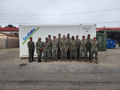 A group of uniformed military personnel stands in front of a white storage container labeled "SeaCube," showcasing the importance of the $3.935 million state grant for Port of Hueneme as Governor ramps up California's Port Data Partnership Program.