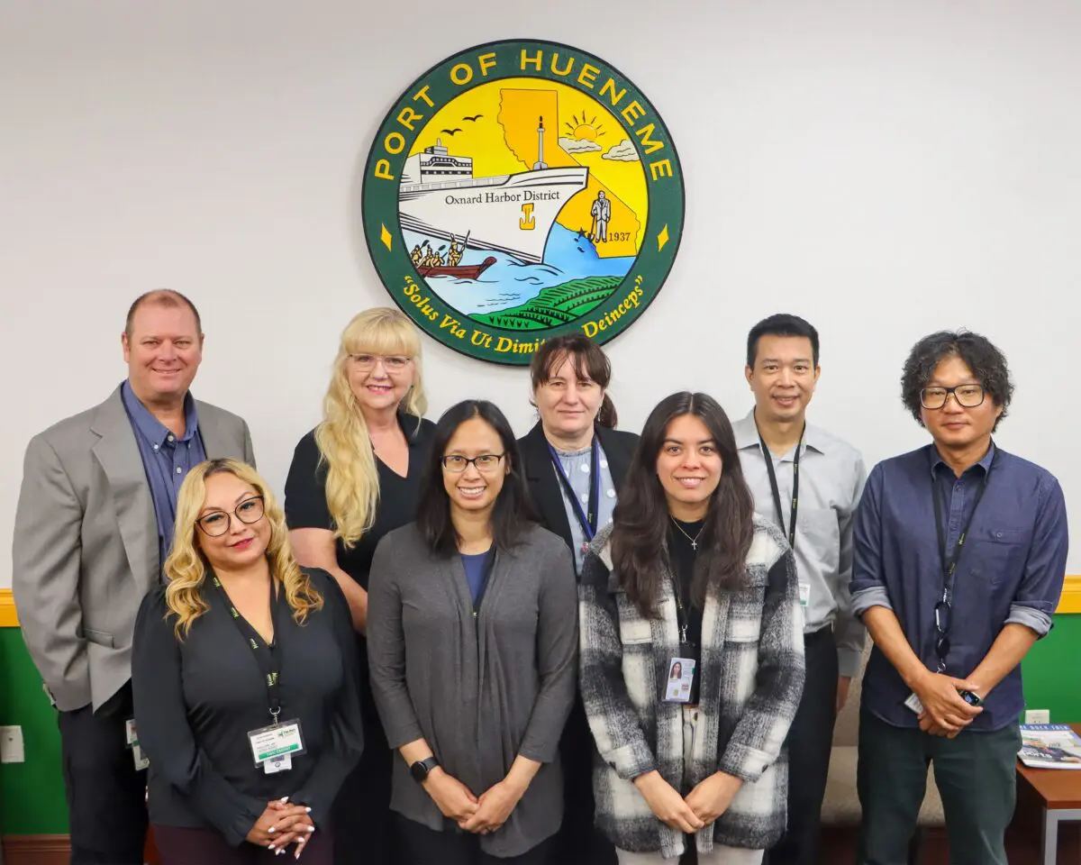 Eight people stand in front of a wall with the Port of Hueneme logo, celebrating a $3.935 million state grant as the Governor ramps up the California Port Data Partnership Program.