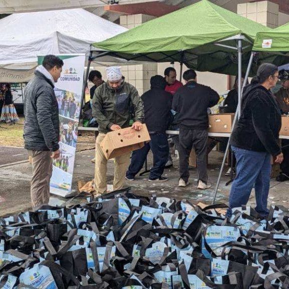 Under green tents, people distribute boxes and bags at an outdoor event, celebrating the $3.935 million state grant for Port of Hueneme as the Governor ramps up California's Port Data Partnership Program.