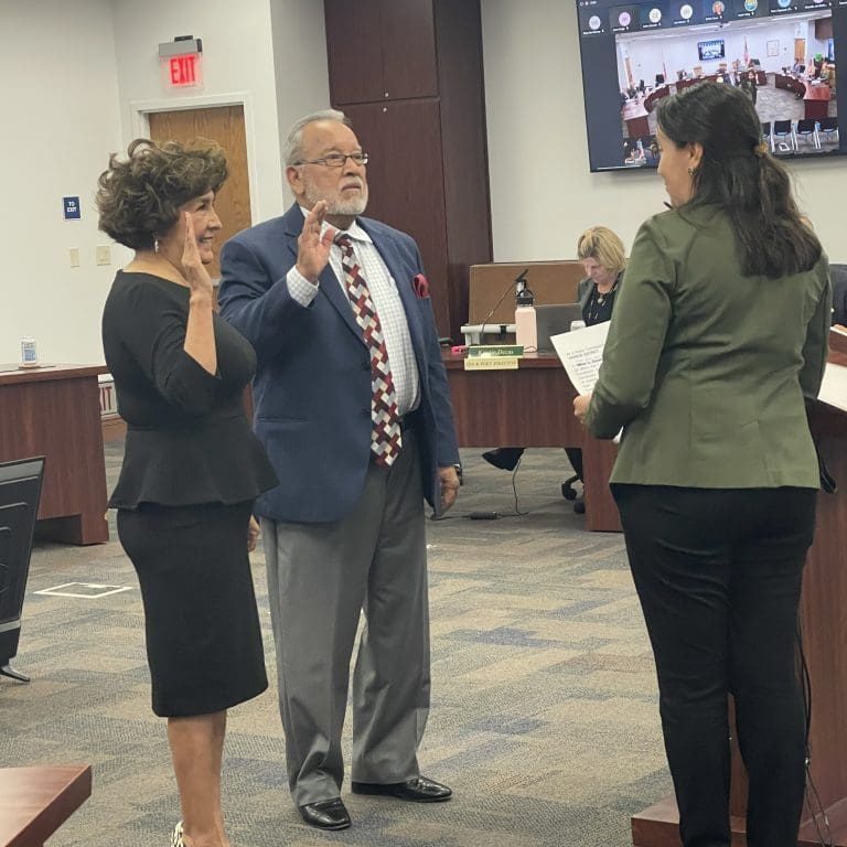 A man in a suit is sworn in by a woman in a green blazer, while another woman raises her hand, marking the announcement of a $3.935 million state grant for Port of Hueneme. A virtual meeting is visible on the screen as Californias port data partnership program gains momentum under the governors initiative.